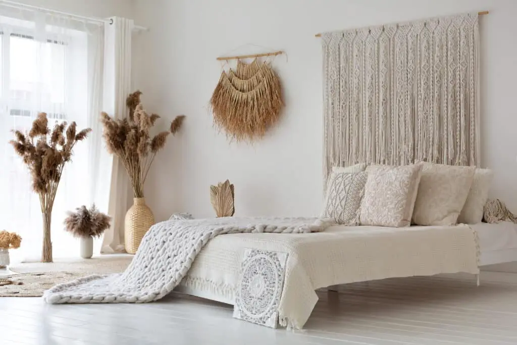 The room is adorned with delicate macramé, dried flora, and neutral tones, perfectly encapsulating Bohemian chic in a minimalist setting.